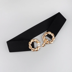 Detail of a black elastic waist belt featuring a textured gold-colored metal buckle clasp