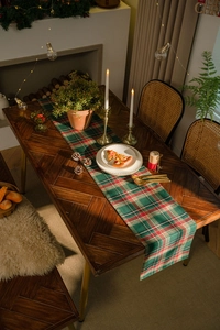Detailed view of red and green plaid table runner with Christmas atmosphere lighting