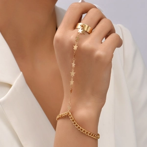Close-up of a gold star charm slave bracelet with Cuban chain and wide ring