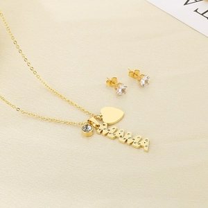 Close-up of gold MAMA necklace and crystal studs on soft fabric background