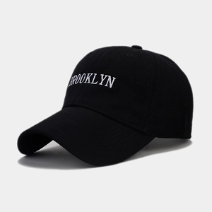 Detailed close-up of white Brooklyn embroidery on a premium black cotton baseball cap
