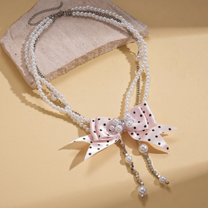 Detail of double-layer pearl necklace with a pink polka dot ribbon bow and heart pendant