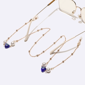 Gold chain glasses strap with white pearls and blue evil eye heart charms on white background