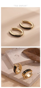 Macro detail of gold geometric hoop earrings with black zircon stones on stone background