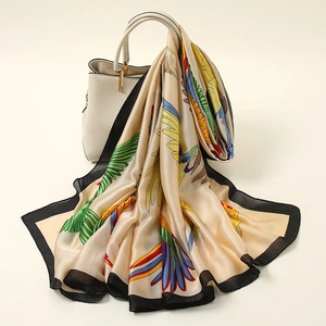 Detailed view of a silky floral scarf with bird print draped over a stylish handbag