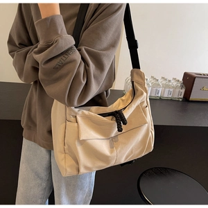 Detail view of khaki canvas crossbody bag with wide black strap and front pocket