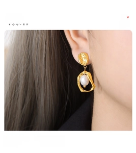 Macro view of gold lava texture earring with round pearl in surgical titanium steel