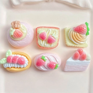 Detailed flat lay of strawberry resin dessert charms on a light pink tray