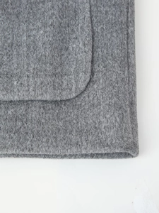 Close-up of thick grey wool blend fabric texture on the coat pocket area