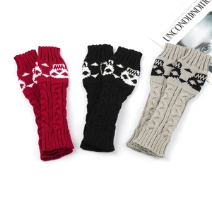 Close-up of three knitted skull fingerless gloves in red, black, and beige colors