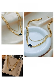 Detail of double-layer gold chain necklace featuring a rectangular black stone pendant