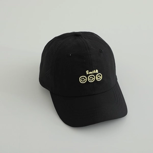 Detail showing black baseball cap with yellow Smile text and three smiley faces embroidery