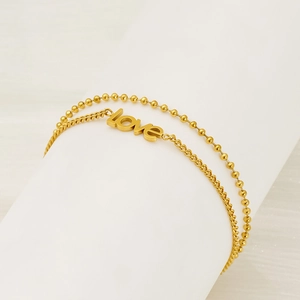 Detail of double-layer golden bead chain and LOVE pendant on a white display stand