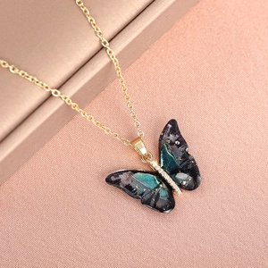 Macro detail of gold butterfly pendant with starry gradient wings and diamond accents