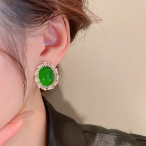 Close-up of vintage oval emerald green stud earrings with diamond accents on model