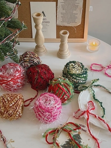 Close-up of DIY Christmas plush balls in red and green with metallic tinsel details