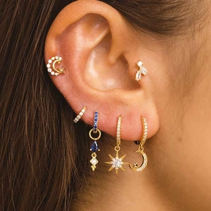 Detail of silver gold-plated butterfly and moon piercing earrings with blue zircons