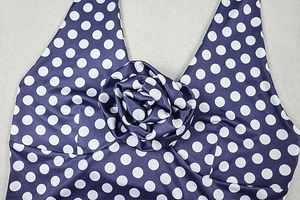 Close-up of purple polka dot halter top with a 3D floral accent on the neckline