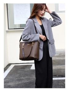Brown retro patterned tote bag with gold hardware shown as crossbody style on a model