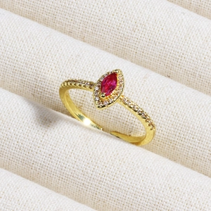 Macro shot of gold ring featuring marquise red gemstone with sparkling diamond halo