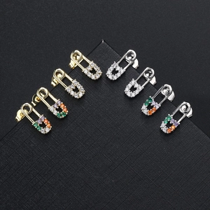 Detailed view of gold and silver paperclip earrings set with white and multi-colored zircons
