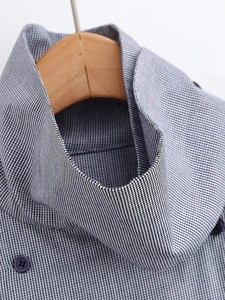 Macro shot of high-neck plaid shirt featuring button trim and black-and-white check pattern