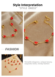 Detailed view of gold stainless steel jewelry set with red heart enamel charms on silk