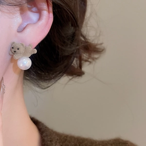Close-up of brown flocked bear stud earring with pearl drop on ear model side view
