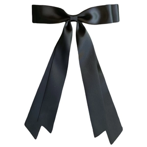 Close-up of a glossy black satin ribbon bow hair clip with elegant balletcore style