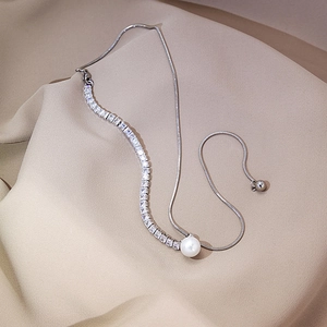 Detail view of silver snake chain necklace with square zircons and white pearl accents