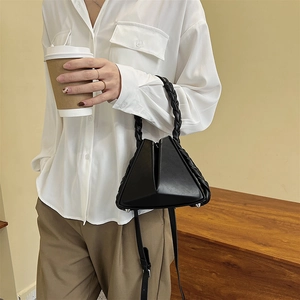 Modern black geometric handbag with woven handle for women on urban lifestyle scene