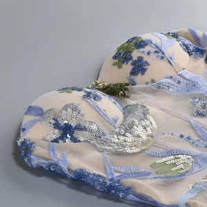 Detailaufnahme der Blumenstickerei und blauen Pailletten auf dem Netz-Abendkleid