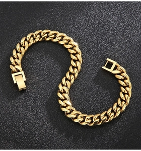 Detailed view of golden Cuban link bracelet with square press clasp on a textured surface