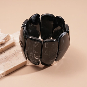 Detail of acrylic bracelet with black and white marble pattern on stone background