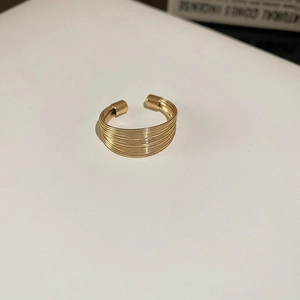 Close-up of golden multi-layer coil ring on a minimalist white surface background