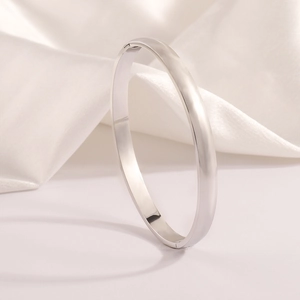 Detail of high-polished silver stainless steel bangle on elegant white silk background