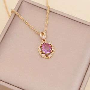 Macro detail of gold flower pendant with pink oval stone and white crystal accents