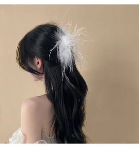 Detailed view of fluffy white ostrich feather hair claw clip on model's dark hair