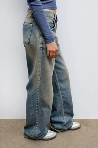 Détail d'un jean large à taille haute avec délavage vintage et coutures latérales
