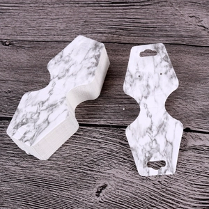 Macro detail of white marble pattern jewelry display cards on a wooden surface