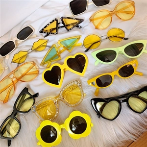 Flat lay of colorful flower-shaped and geometric sunglasses on white fabric