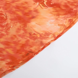 Detailed close-up of precise double-stitched hem on vibrant orange-red tie-dye fabric