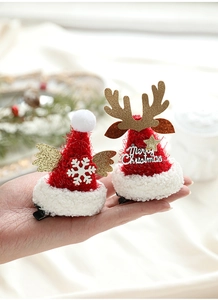 Détail de barrettes bonnet de Noël en peluche rouge avec bois de renne dorés et étoiles