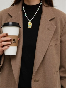 Détail d'un collier de perles d'été avec perles bleu clair et pendentif soleil doré