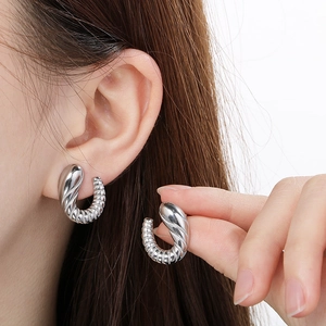 Detailed view of silver croissant style earrings with spiral texture on female model