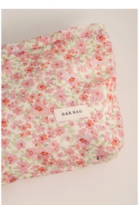Close-up of floral makeup bag featuring H&R BAG woven label and soft cotton texture