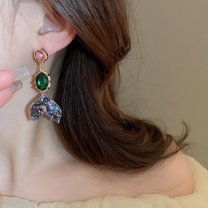 Close-up of model wearing colorful mermaid tail earrings with pink, green and blue gems