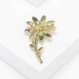 Detailed back view of a gold floral daisy brooch showing the secure pin buckle fastener