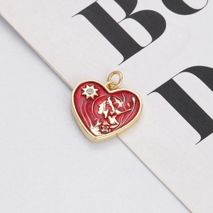 Close-up of heart-shaped gold pendant with red enamel, star pattern and small rhinestone
