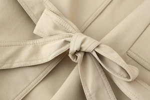 Detailed macro view of the knotted waist belt on a khaki trench coat for women